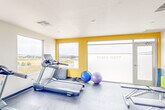 The Parke West Fitness Center at 1060 Village Dr in Santa Maria, California, is a thoughtfully designed community gym offering a comprehensive workout environment within a single open floor. The space features a clean, modern aesthetic with white walls accented by bold yellow panels that add a vibrant energy to the room. Large picture windows line multiple walls, flooding the interior with natural light and providing sweeping views of the surrounding Santa Maria landscape, including rolling hills and open fields.

The fitness floor is covered in durable rubber flooring and is well-organized to accommodate a full range of exercise options. Cardio equipment includes multiple Spirit treadmills, a stationary bike, and an elliptical machine, all positioned to take advantage of the scenic outdoor views. Strength training is supported by a multi-station cable machine, a dumbbell rack with free weights, and a weight bench. Additional workout accessories such as exercise balls, resistance equipment, and yoga/stretching mats are neatly stored and accessible. A wall-mounted flat-screen television is available for entertainment during workouts. A full-length mirror enhances the sense of openness, while the Parke West branding is prominently displayed on frosted glass near the entrance, reinforcing the facility's community identity.