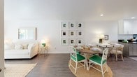 This thoughtfully designed 1-bedroom, 1-bathroom residence offers a functional and stylish layout across a single floor. The kitchen is a standout feature, finished in a U-shaped configuration with two-tone cabinetry — crisp white upper cabinets paired with soft gray lowers — complemented by dark granite countertops, stainless steel appliances, and tile flooring. A window above the sink brings in natural light and views of surrounding greenery. The open living and dining area flows seamlessly, showcasing rich hardwood-style flooring, bright white walls, and recessed lighting. The dining space accommodates a round wooden table with vibrant green accent chairs, while a gallery wall of framed artwork adds a curated touch to the room. The bedroom features plush carpeting, a ceiling fan, and a large window that fills the room with natural light. A mirrored sliding closet provides generous storage. The full bathroom is clean and classic, featuring white subway tile surrounding a tub-shower combination with chrome fixtures and a crisp, neutral palette. Throughout, the residence maintains a bright, cohesive aesthetic with warm, inviting details.