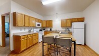 Located at 3433 28th St S in Moorhead, Minnesota, this single-floor residence offers a thoughtfully designed layout that maximizes functionality across its comfortable footprint. The open kitchen is a standout feature, showcasing warm oak cabinetry, white appliances including a range, microwave, dishwasher, and refrigerator, light hardwood flooring, and a butcher-block island with bar seating — ideal for casual dining and meal prep. A double-basin sink and ample counter space add to the kitchen's practicality. The living room features plush carpeting, a ceiling fan, and a sliding glass door that fills the space with natural light and provides direct outdoor access. The generously sized primary bedroom is carpeted and offers a calm, neutral atmosphere. A dedicated office with a window and carpet provides a quiet workspace. Two bathrooms include tile flooring and shower/tub combinations with accessibility grab bars. The in-unit laundry room features full-size washer and dryer units with overhead cabinetry and tile flooring for easy maintenance. Throughout the residence, clean white walls, warm wood trim, and consistent finishes create a cohesive and inviting environment.