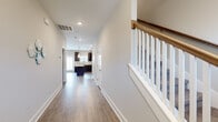 This two-story home is designed with a clean, contemporary aesthetic that balances functionality and comfort throughout both levels. The main floor centers around an open-concept kitchen and dining area, where dark espresso cabinetry pairs with light granite countertops and a central island topped with stylish pendant lighting. Black appliances complement the kitchen's bold contrast, while durable wood-look flooring extends through the main living and dining areas, lending warmth and cohesion. A long hallway connects the main areas and leads to the staircase, which features a classic white baluster railing with a warm wood handrail.

Upstairs, the bedrooms are finished with plush carpeting and benefit from vaulted ceilings that lend a sense of spaciousness. Natural light filters in generously through large windows fitted with blinds, offering both brightness and privacy. The primary bedroom is accompanied by a walk-in closet outfitted with wire shelving along multiple walls, providing ample organization. The bathrooms are consistently finished with stone-look tile flooring, dark vanity cabinetry, granite countertops, and tub-shower combinations, maintaining a cohesive and polished style throughout the home.