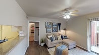 This single-floor residence offers a thoughtfully designed layout that maximizes both comfort and functionality. The living room serves as the heart of the home, featuring rich hardwood-style flooring, a ceiling fan with integrated lighting, and a curated gallery wall that adds a personalized touch. A doorway leads to a well-organized walk-in closet area, adding practical storage to the space.

The galley-style kitchen is efficiently designed with white cabinetry lining both sides, offering generous storage and counter space. It is equipped with a full suite of appliances, including an electric range, refrigerator, and dishwasher, all complemented by hardwood-style flooring that ties the space together.

The two bedrooms are carpeted for warmth and comfort, each featuring ceiling fans, natural light from exterior-facing windows, and views to the outdoors. The rooms provide a calm and restful atmosphere, ideal for relaxation.

The bathroom is well-appointed with a wide vanity countertop, a large mirror, and hardwood-style flooring, offering both style and practicality. The neutral color palette throughout the residence creates a cohesive, welcoming ambiance that is both modern and timeless.