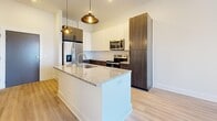Located at 7 Vance Avenue in Memphis, Tennessee, this well-appointed one-bedroom, one-bathroom residence offers a thoughtfully designed layout across a single floor. Light-toned luxury vinyl plank flooring flows consistently throughout the space, creating a cohesive and modern aesthetic.

The kitchen is a standout feature, showcasing a two-tone cabinetry design with dark wood lower cabinets and crisp white upper cabinets. A granite-topped island with an integrated sink serves as both a functional workspace and a visual centerpiece, illuminated by stylish pendant lighting. Stainless steel appliances, including a French door refrigerator, electric range, and microwave, complete this contemporary kitchen.

The living area provides access to a private balcony through double glass doors, allowing natural light to pour in while offering outdoor views of the surrounding cityscape. A ceiling fan adds comfort to this open, airy space.

The bedroom is generously proportioned, featuring a large grid-pane window with water views, contributing to a bright and serene atmosphere. It connects directly to a dedicated walk-in closet equipped with multi-tier wire shelving and hanging rods, offering substantial storage capacity.

The bathroom features a distinctive blue vanity with granite countertops, a framed mirror, and a sliding barn-style shower door, blending practicality with modern design detail.