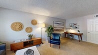 This single-floor residence in Pleasanton, California offers a thoughtfully designed layout with a seamless flow between living, dining, and kitchen areas. The living room features plush carpeting, a textured ceiling, and a large window that invites natural light and outdoor views, creating a warm and welcoming atmosphere. Mid-century modern decor accents complement the neutral color palette throughout.

The kitchen is outfitted with white shaker-style cabinetry, granite-look countertops, stainless steel appliances including a refrigerator, dishwasher, microwave, and range, and durable wood-style flooring. Adjacent to the kitchen, the dining area accommodates a full-sized table and benefits from a window overlooking the exterior.

The primary bedroom is generously sized with soft carpet, mirrored sliding closet doors, and room for a full furniture suite. A second bedroom offers carpet flooring, a window with views of the surrounding greenery, and a mirrored closet. The bathroom is clean and updated, featuring white cabinetry, granite countertops, wood-style flooring, and a shower-tub combination. A flexible room serves well as a home office or study, complete with carpet and built-in shelving.