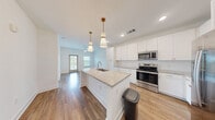 Located at 7785 Griffon Ln in Vero Beach, Florida, this well-designed one-bedroom, one-bathroom residence offers a thoughtfully organized single-floor layout that maximizes every square foot of living space.

The kitchen serves as the centerpiece of the home, showcasing a large granite-topped island with a built-in sink and elegant pendant lighting overhead. Crisp white shaker cabinetry extends to the ceiling, providing ample storage, while stainless steel appliances — including a range, microwave, and French door refrigerator — complete the modern, functional design. Warm hardwood-style flooring runs throughout the main living areas, lending continuity and a clean aesthetic.

The bedroom is a comfortable retreat, finished with plush carpeting, a ceiling fan with light fixture, and a window that frames natural outdoor views and fills the room with natural light. A dedicated closet offers practical storage, keeping the space organized and efficient.

The bathroom is finished with white cabinetry, a granite vanity countertop, a large mirror, and matching hardwood-style flooring, creating a clean and polished atmosphere. The overall design palette of crisp whites, warm wood tones, and stone accents gives the entire residence a bright, modern, and welcoming character.