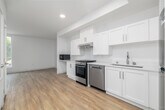 Located at 1999 W 3rd St in the heart of Los Angeles, this thoughtfully designed studio offers a clean, modern aesthetic across a single level. Light wood-style flooring runs throughout the entire space, creating a cohesive and warm ambiance. The open-concept kitchen and living area forms the core of the unit, featuring white shaker cabinetry, white countertops, a stainless steel gas range, dishwasher, refrigerator, and a range hood — providing a fully equipped cooking space within a bright, efficient layout. Recessed lighting illuminates the kitchen area, while the living space benefits from large windows that invite abundant natural light and offer views of surrounding greenery. The entry hallway connects to two closets, offering generous storage for a compact space, along with easy access to the main living and kitchen zones. The bathroom is outfitted with accessibility-forward features, including multiple grab bars alongside the shower/tub combination and toilet, complemented by the same light wood flooring that carries throughout the unit. Crisp white walls across all areas reinforce the bright, clean character of the space. This studio presents a practical and well-appointed layout well-suited for urban Los Angeles living.