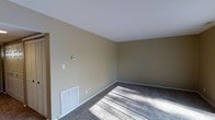 This two-floor residential space offers a straightforward and functional layout designed for comfortable everyday living. The interior features neutral, warm beige-toned walls that create a calm and understated ambiance throughout. Carpet flooring runs across the living areas, adding a layer of softness and warmth underfoot, while white baseboards provide a clean contrast against the walls.

The space is equipped with a wall-mounted thermostat, indicating a central climate control system, along with floor-level HVAC vents that ensure consistent heating and cooling throughout the rooms. The ceilings are smooth and white, contributing to a clean, bright overhead finish that helps reflect natural light filtering in through the windows.

The open, uncluttered layout of the main living area provides a versatile canvas, easily adaptable to a variety of furniture arrangements and personal styles. The two-floor configuration offers a natural separation between living and private spaces, a practical feature that supports both daily activity and rest. Overall, the space presents a clean, move-in ready environment with essential systems in place and a neutral palette that accommodates a wide range of interior design preferences.