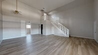 Located at 6419 Skyline Dr in Houston, TX, this two-story, 2-bedroom, 2-bathroom home offers a well-organized layout spread across two floors. The expansive main floor hosts the living room, dining room, kitchen, entrance, and hallway. The living room is a standout space, featuring soaring ceilings, light wood-look flooring, and abundant natural light filtered through windows with blinds. A striking white-railed staircase with carpeted treads serves as a central architectural feature, leading to the upper level with an open balcony overlooking the main floor below. The kitchen is equipped with granite countertops, a tile backsplash, and dark cabinetry. The upper floor houses both bedrooms, each with ceiling fans and light wood flooring. The spacious primary bedroom includes a walk-in closet with full rod and rail storage. The second bedroom features a vaulted ceiling, adding character and a sense of openness. Three closets throughout the home provide ample storage. The bathrooms are finished with granite vanity tops and tiled tub-shower surrounds. The home also includes built-in shelving in the living area, adding functional display space to this clean, neutral-toned residence.