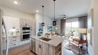 This well-appointed single-story residence showcases a thoughtfully designed open-concept layout that seamlessly connects the kitchen, dining, and living areas. The kitchen is a standout feature, equipped with stainless steel appliances including a double wall oven and built-in microwave, complemented by two-tone cabinetry that pairs white upper cabinets with wood-grain lower units. Granite countertops extend across the workspace and onto a central island fitted with a undermount sink, illuminated by two stylish pendant lights overhead. Wood-grain flooring flows throughout the main living areas, adding warmth to the space.

The living room is bright and inviting, benefiting from a large sliding glass door that opens to a private balcony with outdoor views. A ceiling fan adds comfort to the room, which also features neutral-toned walls and elegant floor-length drapes.

The residence includes two carpeted bedrooms, each with multiple windows that allow generous natural light and offer exterior views. Both rooms provide ceiling fans and ample closet storage with built-in shelving. The bathroom features a full soaking tub and shower combination with textured tile surround and wood-look flooring, completing this well-balanced and modern living space.