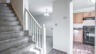 This two-story home offers a well-organized layout across both levels, combining functional design with comfortable living spaces throughout. The kitchen is equipped with warm honey-toned wood cabinetry, dark granite-style countertops, hardwood-style flooring, and black appliances including a range, dishwasher, and refrigerator. A window above the sink brings in natural light and views of surrounding greenery, while the adjacent staircase connects seamlessly to the upper level. The main living area is generously sized, featuring plush carpeting, a fireplace, built-in shelving, and a chandelier that adds a touch of elegance. A sliding glass door opens to the outdoors, flooding the room with natural light and providing direct exterior access. The bathrooms are clean and practical, each featuring a vanity with a wide mirror, a toilet, and a shower enclosure. The bedrooms are well-proportioned with soft carpet flooring, textured ceilings, and ample closet space. Several bedrooms benefit from multiple windows that invite natural light and views of the surrounding trees. The upper-level bedrooms include access to adjoining bathrooms, adding convenience. Overall, the home presents a straightforward and livable floor plan suited for everyday comfort.