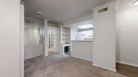 Located at 6233 Love Dr in Irving, TX, this one-bedroom, one-bathroom unit offers a thoughtfully designed single-floor layout with a warm, neutral palette throughout. The open-concept living area features plush carpeting, crown molding, decorative pillar accents, and a ceiling fan, creating a comfortable and inviting atmosphere. Built-in shelving provides convenient display and storage space, while a mirrored wall feature adds a sense of depth to the room. The front entry opens directly into the living space, which flows seamlessly toward the kitchen pass-through.

The kitchen is well-appointed with white cabinetry, stone-toned countertops, a full suite of white appliances including a refrigerator and electric range, a stainless sink, and durable wood-look vinyl flooring. A skylight overhead brings in natural light, brightening the cooking space.

The bedroom is a comfortable retreat with carpet flooring, a ceiling fan, and a window fitted with blinds. It is accessible through double doors and connects to a generous walk-in closet outfitted with wire shelving on multiple walls for ample storage.

The bathroom features wood-look vinyl flooring, white cabinetry, stone-toned countertops, a large vanity mirror with overhead lighting, and clean, bright finishes throughout.