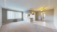 Located at 14210 Cedar Rd in University Heights, Ohio, this single-floor unit offers a practical and functional layout throughout. The living area is generously sized, featuring neutral gray walls, plush carpeting, and a ceiling fan overhead. A tray ceiling detail adds subtle architectural interest, while a large window with vertical blinds allows natural light to fill the space. The transition between the living and dining areas is marked by a shift from carpet to light ceramic tile flooring.

The kitchen is efficiently designed with warm oak cabinetry lining both walls, white countertops, and a pass-through opening that connects to the main living area. White appliances, including a gas range and dishwasher, are provided, and two windows offer views of the surrounding neighborhood. A peninsula adds additional counter space and enhances the open feel between the kitchen and adjacent areas.

The bedrooms are carpeted and well-proportioned, with neutral-toned walls and ample natural light from multiple windows. One bedroom features dual closets with warm wood sliding doors, providing generous storage. A ceiling fan is present in one bedroom for added comfort.

The bathroom is fully tiled in white, featuring an oak vanity with under-cabinet storage, a mirror, a tub-shower combination, and a small window for natural ventilation.