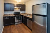 Located at 4101 Dayton Blvd in Red Bank, Tennessee, this single-floor unit offers a well-organized layout with a clean, neutral aesthetic throughout. The living area is bright and open, featuring rich hardwood-style flooring and soft gray walls that create a calm, airy atmosphere. Vertical blinds dress a sliding glass door that invites natural light and provides access to the outdoors. The living space flows seamlessly into a secondary area near the front entry, maintaining the same warm flooring and open feel.

The kitchen is thoughtfully appointed with dark espresso cabinetry, granite-style countertops, and a full suite of stainless steel appliances including a range, dishwasher, and refrigerator. Track and flush-mount lighting keep the space bright and functional.

The bedroom offers plush carpeting underfoot and is equipped with a ceiling fan with light fixture, providing comfort year-round. A closet provides convenient built-in storage.

The bathroom is finished with hardwood-style flooring consistent with the rest of the unit and features a full tub-and-shower combination with clean white surrounds, providing a practical and tidy space. Throughout, white trim and baseboards lend a crisp, finished look to every room.