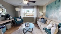 This thoughtfully designed single-floor residence showcases a cohesive coastal-inspired aesthetic carried throughout its well-appointed rooms. The living area serves as the heart of the home, featuring wood-look flooring, a ceiling fan, and a large window framing a serene water view flanked by lush palm trees — a standout feature that fills the space with natural light and a relaxing atmosphere. A glass-top coffee table and teal accent chair complement the neutral tones, creating an inviting and sophisticated setting.

The galley-style kitchen is efficiently laid out with white cabinetry, granite-style countertops, stainless steel appliances including a refrigerator, range, and dishwasher, and warm wood-look flooring that ties seamlessly into the rest of the home. Adjacent to the kitchen, the dining area accommodates a round glass table surrounded by teal upholstered chairs, with a striking large-format abstract artwork adorning the wall. A laundry closet is conveniently accessible nearby.

Both bedrooms are generously proportioned, each featuring wood-look flooring, ceiling fans, and large windows with views of tropical landscaping. The bathrooms are clean and functional, each offering a tub-shower combination, wood-look flooring, and vanities with granite-style countertops. The overall ambiance is bright, modern, and cohesive throughout.