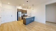 Located at 4101 Central Ave NE in Albuquerque, NM, this thoughtfully designed 2-bedroom, 2-bathroom residence offers a clean, contemporary aesthetic across a single floor. The open-concept main living area seamlessly connects the living room, dining space, and kitchen, all finished with light-toned hardwood-style flooring that enhances the sense of brightness throughout. The modern kitchen is a standout feature, showcasing dark wood cabinetry, granite countertops, a large center island with a built-in sink and dishwasher, and a full suite of stainless steel appliances, including a refrigerator and gas range. Stylish pendant lighting above the island adds a refined finishing touch. Both bedrooms feature plush carpet flooring, ceiling fans, and natural light from well-placed windows. The spacious primary bedroom includes its own en-suite bathroom with a granite-topped vanity and dark cabinetry, plus direct access to a generous walk-in closet. The second bathroom offers a tiled tub-shower combination. Additional conveniences include three closets, an in-unit laundry area, a connecting hallway, and a private patio. The unit's crisp white walls and modern finishes create a clean, move-in-ready atmosphere throughout.