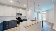 Located at 3229 W Montague Ave in North Charleston, SC, this single-floor residence offers a thoughtfully designed layout comprising one bedroom, one bathroom, a kitchen, and an open living area. The kitchen is a standout feature, showcasing a striking two-tone cabinetry design with crisp white upper cabinets and deep navy lower cabinets. A granite-topped island with an undermount sink serves as the centerpiece, complemented by pendant lighting overhead. Stainless steel appliances — including a refrigerator with ice maker, electric range, microwave, and dishwasher — complete the kitchen. Light wood-style flooring runs throughout the main living and kitchen areas, adding warmth and continuity. The living area flows naturally from the kitchen and is brightened by a window with blinds and a ceiling fan. The spacious primary bedroom features soft carpeting, a ceiling fan, and access to a walk-in closet. The bathroom is finished with a dual-sink vanity topped with granite, navy cabinetry, light wood-style flooring, and a tub/shower combination with a curved curtain rod. Neutral wall tones throughout create a clean, modern ambiance well-suited for comfortable everyday living.