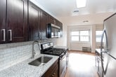 Located at 2175 Hudson Terrace in Fort Lee, New Jersey, this single-floor residence offers a clean, modern aesthetic throughout its thoughtfully designed layout. Warm hardwood flooring runs continuously across the living spaces, lending a sense of cohesion and comfort to the interior.

The kitchen is a functional highlight, outfitted with rich dark-stained cabinetry, granite-style countertops, a classic subway tile backsplash, and stainless steel appliances including a gas range, microwave, and refrigerator. Overhead lighting brightens the workspace, and the layout allows for efficient movement and storage.

The living and bedroom areas are generously proportioned, featuring crisp white walls, natural light from large windows, and in-unit heating and cooling units. One bedroom offers direct access to an en-suite bathroom, adding a layer of privacy and convenience.

The unit includes two bathrooms. The primary bathroom features a tiled shower stall with a glass enclosure, a dark wood vanity with a white basin sink, a mirrored medicine cabinet, and hexagonal tile flooring. The second bathroom is appointed with a full soaking tub and shower combination, large-format tile surround, and a matching dark wood vanity. Both bathrooms maintain a consistent, contemporary design palette throughout.