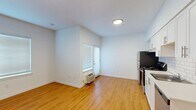 This 390 square foot apartment in Portland, Oregon offers a thoughtfully designed living space on a single floor. The kitchen is a standout feature, boasting crisp white cabinetry complemented by a subway tile backsplash. Stainless steel appliances, including a full-size refrigerator, range, and dishwasher, add a modern touch. The bathroom continues the clean aesthetic with white subway tiles surrounding the bathtub and shower combination. A wall-mounted cabinet provides storage above the toilet. The unit includes the convenience of in-unit laundry facilities. Throughout the apartment, warm wood flooring creates a cohesive look and adds a touch of natural warmth. The open layout maximizes the use of space, with the kitchen area flowing into the main living area. Recessed lighting and a central ceiling fixture ensure ample illumination. While compact, the apartment's efficient design and contemporary finishes make it an attractive option for urban living in Portland's St. Johns neighborhood.