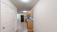 Located at 1150 Brampton Ave in Statesboro, Georgia, this single-floor unit offers three bedrooms and three bathrooms within a well-organized layout. The kitchen is a functional galley-style space featuring warm honey-toned wood cabinetry, granite-style countertops, a classic white subway tile backsplash, and a full suite of black appliances including a refrigerator, range, over-the-range microwave, and dishwasher. Durable wood-look flooring runs throughout the kitchen and hallway, lending a cohesive and easy-to-maintain aesthetic. The hallway connects the main living areas, providing smooth transitions between rooms. Each of the three bedrooms is finished with plush carpet flooring and equipped with a ceiling fan and light fixture, offering comfort and air circulation. Windows in each bedroom allow for natural light and outdoor views. The primary bedroom provides a comfortable and private retreat. All three bathrooms share a consistent design, featuring tiled flooring, a vanity with warm wood cabinetry, a white countertop, and a full tub-shower combination with clean white surrounds and chrome fixtures. The overall ambiance is clean, neutral, and move-in ready, making this a practical and comfortable home.