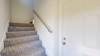 Located at 3205 Fairfax St in Eau Claire, WI, this two-story, one-bedroom, one-bathroom unit offers a well-organized layout across two levels. The ground floor houses a private attached garage with an automatic opener, concrete flooring, and interior access — providing convenient and secure parking or additional storage space.

The main living level features an open, light-filled layout with warm hardwood-style flooring in the main living and kitchen areas. The contemporary kitchen is a standout, showcasing crisp white shaker cabinetry, a striking hexagonal tile backsplash, stainless steel appliances including a refrigerator, range, and microwave, and a peninsula with a quartz countertop and undermount sink — ideal for both meal prep and casual dining.

The bedroom is a comfortable retreat with plush carpeting, a ceiling fan, a baseboard heater, and a window that invites natural light and a view of the surrounding neighborhood. The full bathroom is cleanly designed with large-format gray tile flooring, a white tub-shower combo, and a vanity with white cabinetry. A hallway and staircase connect the spaces efficiently.

Outside, a fenced yard with green landscaping adds a pleasant outdoor element to this neatly appointed Eau Claire residence.