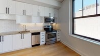 Located at Pickwick Plaza in downtown Kansas City, Missouri, Unit 517 is a thoughtfully designed single-floor residence featuring contemporary finishes and a clean, minimalist aesthetic. Light-toned hardwood flooring runs consistently throughout the space, providing a warm and cohesive foundation for each room.

The kitchen is a standout feature, equipped with stainless steel appliances including a range, over-the-range microwave, dishwasher, and refrigerator. White flat-front cabinetry extends to the ceiling, maximizing storage, while granite countertops and a classic white subway tile backsplash add texture and visual interest. The kitchen opens directly to a generously sized living area, which benefits from multiple black-framed windows that invite abundant natural light and offer views of the surrounding urban streetscape.

The bedroom areas are well-proportioned, each featuring large windows that frame city views and provide excellent daylighting. The rooms maintain the same clean white walls and hardwood flooring found throughout the unit, creating a consistent and polished feel.

The bathroom is finished with full white subway tile surrounding a soaking tub and shower combination enclosed by sliding glass doors, complementing the unit's modern design language. A dedicated corridor connects the main living spaces, offering a practical and organized flow. Overall, the unit presents a bright, move-in-ready environment with quality finishes and a refined urban character.
