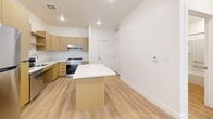 Located at 856 25th St in Ogden, Utah, this thoughtfully designed one-bedroom, one-bathroom unit offers a clean, modern aesthetic throughout its efficiently organized single-floor layout. Light wood-tone flooring flows seamlessly through every room, complementing the crisp white walls and recessed lighting that keep the space bright and welcoming.

The open-concept living area integrates the dining room, kitchen, and living space into one cohesive zone. The kitchen is a standout feature, equipped with warm-toned wood cabinetry, stainless steel appliances including a refrigerator, range, dishwasher, and microwave, as well as a central island with a white countertop — ideal for both meal prep and casual dining. A sliding glass door with vertical blinds opens the living area to outdoor views and fills the space with natural light.

The bedroom is a comfortable, well-proportioned retreat featuring large windows with horizontal blinds and a ceiling fan, allowing for ample natural light and airflow. The bathroom is designed with accessibility in mind, featuring an open-concept vanity with warm wood drawers, a wide mirror with overhead lighting, and a full bathtub with grab bars.

Additional highlights include a dedicated laundry room with a full-size washer and dryer, a separate closet for storage, and a consistent, modern design palette throughout.