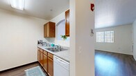 Located at 701 White Spar Rd in Prescott, Arizona, this single-story, 2-bedroom, 1-bathroom residence offers a well-organized and functional layout. The combined kitchen and living area serves as the heart of the home, where a galley-style kitchen features warm wood-toned cabinetry lining both walls, ample counter space, a double-basin sink, a dishwasher, and a full range with overhead storage. A charming arched pass-through connects the kitchen to the living area, enhancing the open flow between spaces. Wood-style flooring runs throughout the home, lending warmth and visual continuity to every room. Both bedrooms are bright and well-proportioned, with large windows fitted with vertical blinds that frame views of surrounding trees and allow generous natural light. The primary bedroom is notably spacious and includes a walk-in closet with dual wire-rack shelving systems, offering exceptional storage capacity. Additional closet space is found throughout the unit, with a total of five closets providing practical storage solutions. The bathroom features a light wood-tone vanity, a tub/shower combo, and clean, neutral finishes. A connecting hallway ties the rooms together efficiently. The overall ambiance is clean, neutral, and move-in ready, well-suited for comfortable everyday living in a serene Prescott setting.