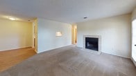 This single-floor residence offers a functional and comfortable layout across several well-defined living spaces. The living room serves as a central gathering area, anchored by a tile-surround fireplace with a classic black insert, adding warmth and character to the space. Neutral-toned carpet extends throughout the living and bedroom areas, creating a cohesive feel underfoot, while textured ceilings add subtle visual depth.

The galley-style kitchen is efficiently arranged with warm wood-toned cabinetry, white laminate countertops, and wood-look flooring that provides a clean contrast to the surrounding spaces. A full suite of appliances, including a dishwasher and refrigerator, is included. A pass-through view connects the kitchen to adjacent areas, enhancing the sense of flow.

The bedrooms are generously proportioned, each equipped with ceiling fans featuring integrated light fixtures for added comfort and convenience. Natural light filters in through windows fitted with blinds.

Two full bathrooms serve the residence, each featuring a tub-shower combination with built-in recessed shelving, complemented by wood-toned vanity cabinetry and warm-toned flooring. The overall design is practical and move-in ready, with a clean, neutral palette throughout that lends itself well to a variety of interior styles.
