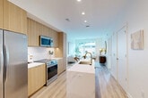 Located in Washington, DC's Chevy Chase neighborhood, this thoughtfully designed 2-bedroom, 2-bathroom residence offers a seamless blend of modern aesthetics and functional living. Light wood flooring flows throughout the single-level floor plan, complementing the clean white walls and recessed lighting that create a bright, airy atmosphere.

The open-concept kitchen, dining, and living area serves as the heart of the home. The kitchen features flat-front light wood cabinetry, a striking marble-look quartz waterfall island with an undermount sink and gold-tone fixtures, and stainless steel appliances. The living area is bathed in natural light from expansive floor-to-ceiling windows offering direct city views.

The generously sized primary bedroom includes a textured accent wall, large windows with urban views, and access to a well-appointed en-suite bathroom featuring a dual-sink floating wood vanity, a frameless glass-enclosed walk-in shower, and large-format tile flooring. Four closets — including spacious walk-in options with built-in shelving systems — provide abundant storage throughout.

Additional highlights include a dedicated den ideal for a home office, in-unit laundry, and a second full bathroom. The residence offers a refined, contemporary lifestyle in one of DC's most sought-after corridors.