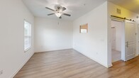 Located at Treviso Grand in Venice, FL, this one-bedroom, one-bathroom unit offers a practical and well-designed single-floor layout. The open-concept kitchen and living area form the heart of the home, showcasing warm-toned wood cabinetry extending to the ceiling for generous storage, light-colored countertops, a double-basin stainless steel sink, and a full suite of stainless steel appliances including a refrigerator, dishwasher, microwave, and electric range. Wood-look plank flooring runs throughout the main living area, lending a clean and cohesive aesthetic. The living space is bright and airy, with multiple windows fitted with horizontal blinds allowing natural light to filter in, complemented by a ceiling fan with a light fixture overhead. The bedroom is carpeted for comfort and features a sliding double-door closet, a ceiling fan, and a window with views of the surrounding greenery. The bathroom is finished with crisp white walls, wood-look flooring, a dark-toned vanity with white countertop, a wall-mounted mirror, and a glass-enclosed walk-in shower with tile surround and built-in shelving. The unit's neutral palette and modern finishes create a clean, move-in-ready living environment.
