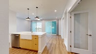 Located at 11464 Alamo Ranch Parkway in San Antonio, TX, this thoughtfully designed one-bedroom, one-bathroom residence offers a clean, modern aesthetic with warm, cohesive finishes throughout. Light-toned hardwood-style flooring runs continuously across every room, creating a seamless and inviting atmosphere.

The open-concept kitchen and living area serves as the heart of the space. The kitchen features warm wood cabinetry, a crisp white farmhouse sink set into a generous island, sleek white countertops, stainless steel appliances — including a refrigerator, range, and microwave — and a dedicated pantry. Stylish pendant lights hang above the island, adding a contemporary touch. The living area flows naturally toward sliding glass doors that open to a private patio with outdoor views.

The bedroom is well-proportioned, offering a ceiling fan, a sliding glass door for added natural light and outdoor access, and direct connectivity to a walk-in closet and the full bathroom. The bathroom is finished with matching wood-tone cabinetry, a white vanity countertop, and a tiled walk-in shower enclosed by a glass door.

Additional highlights include a dedicated laundry area, a bonus room, ample closet storage, and hallways that provide efficient circulation throughout. Recessed lighting throughout the unit completes the polished, move-in-ready presentation.