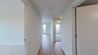This contemporary 820 square foot apartment offers a blend of style and functionality. The open-concept living area is illuminated by large windows, providing ample natural light and impressive city views. The modern kitchen is a standout feature, boasting sleek cabinetry, stainless steel appliances, and a convenient island with additional seating.

The apartment includes two bedrooms, with the primary bedroom measuring 150 square feet. Both bedrooms feature plush carpeting for comfort, while the main living areas showcase durable hardwood flooring. The bathroom is well-appointed with a modern vanity, large mirror, and clean lines.

Storage is thoughtfully incorporated with a dedicated closet space featuring wire shelving. The unit also includes climate control for year-round comfort, evidenced by the presence of a wall-mounted HVAC unit.

Throughout the apartment, neutral tones and minimalist design create a fresh, inviting atmosphere. The strategic layout maximizes the use of space, making this compact apartment feel spacious and airy. Located in Vancouver, WA, this unit offers a perfect blend of urban living and modern comfort.