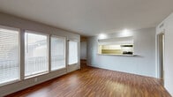 This single-story unit offers a well-organized layout with consistent hardwood-style flooring running throughout every room, lending a warm and cohesive feel to the entire space. The open living area is a standout, featuring a painted white brick accent wall and large windows with blinds that allow abundant natural light to fill the room. A patio door provides direct outdoor access. The pass-through kitchen connects seamlessly to the living area via a breakfast bar with granite-style countertops, and is equipped with black appliances including a coil-top range, dishwasher, and stainless steel refrigerator, complemented by white cabinetry and an overhead range hood. The dining or secondary living area features a ceiling fan with light kit and flows naturally into the rest of the home. Both bedrooms are generously proportioned, each outfitted with ceiling fans. The primary bedroom includes two closets for ample storage. The bathrooms are clean and functional, each featuring a full tub-shower combination with tile surround, chrome fixtures, and white vanity cabinetry with granite-style countertops. The overall aesthetic is bright, neutral, and move-in ready.