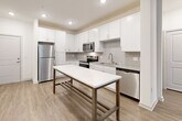 Located at 1521 Lee Rd in Douglasville, GA, this well-appointed single-story home offers three bedrooms, three full bathrooms, a living room, kitchen, laundry room, and three closets — all thoughtfully laid out across a comfortable footprint. The kitchen is a standout feature, boasting crisp white shaker cabinetry, a classic subway tile backsplash, granite countertops, stainless steel appliances including a refrigerator, range, microwave, and dishwasher, and a large white quartz-topped island with a metal frame that doubles as a dining or prep space. Light wood-look flooring flows throughout the main living areas, complementing the clean, modern aesthetic. The living area features a ceiling fan and a glass door that opens to a private outdoor balcony area, inviting natural light and views of surrounding greenery. Bedrooms are carpeted for comfort, with large windows fitted with blinds that allow ample natural light. The primary bedroom offers generous proportions with dedicated closet space. Each bathroom is finished with white cabinetry, granite vanity tops, and wood-look flooring. The bathrooms include a beautifully tiled walk-in shower with marble-style porcelain panels and a frameless glass door. A dedicated laundry room with washer and dryer hookups and overhead shelving adds everyday convenience.