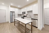 Located at 1521 Lee Rd in Douglasville, GA, this well-appointed single-story home offers three bedrooms, three full bathrooms, a living room, kitchen, laundry room, and three closets — all thoughtfully laid out across a comfortable footprint. The kitchen is a standout feature, boasting crisp white shaker cabinetry, a classic subway tile backsplash, granite countertops, stainless steel appliances including a refrigerator, range, microwave, and dishwasher, and a large white quartz-topped island with a metal frame that doubles as a dining or prep space. Light wood-look flooring flows throughout the main living areas, complementing the clean, modern aesthetic. The living area features a ceiling fan and a glass door that opens to a private outdoor balcony area, inviting natural light and views of surrounding greenery. Bedrooms are carpeted for comfort, with large windows fitted with blinds that allow ample natural light. The primary bedroom offers generous proportions with dedicated closet space. Each bathroom is finished with white cabinetry, granite vanity tops, and wood-look flooring. The bathrooms include a beautifully tiled walk-in shower with marble-style porcelain panels and a frameless glass door. A dedicated laundry room with washer and dryer hookups and overhead shelving adds everyday convenience.