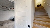 This contemporary multi-level residence spans three floors and offers a thoughtfully designed layout with two bedrooms and three bathrooms. The ground level houses a private garage with exposed concrete floors, a roll-up door, and a window overlooking the waterway — spacious enough to accommodate a golf cart or vehicle.

The main living floor is bright and open, combining the kitchen and living area in a seamless, modern layout. The kitchen features warm wood cabinetry, a marble-style backsplash, stainless steel appliances, and light hardwood flooring that flows throughout. Floor-to-ceiling sliding glass doors open to a balcony with stunning waterfront views, flooding the space with natural light. The living area is anchored by a ceiling fan, neutral tones, and a welcoming open feel.

The upper floor hosts both bedrooms. The primary bedroom is generously proportioned, with large sliding glass doors framing waterway views, a ceiling fan, and a dedicated walk-in closet. The second bedroom is bright with a large window and direct access to its own en-suite bathroom featuring warm wood vanity accents. The bathrooms throughout are finished in marble-style tile with matte black fixtures and tub-shower combinations. A hallway and closet complete the upper level, rounding out a well-organized and stylish residence.