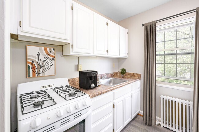 Una cocina blanca con estufa blanca y gabinetes blancos. - Mason Hall