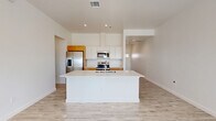 Located at 5602 Shadow Hills Rd in Las Cruces, NM, this single-story 2-bedroom, 1-bathroom home offers a clean, modern aesthetic throughout. Light wood-look tile flooring flows seamlessly across the entire home, complementing the crisp white walls and recessed lighting that create a bright, airy atmosphere.

The open-concept living, dining, and kitchen area serves as the heart of the home. The well-appointed kitchen features warm wood cabinetry, white upper cabinets, a large central island with a white quartz countertop and undermount sink, and a full suite of stainless steel appliances including a refrigerator with ice maker, range, microwave, and dishwasher.

The living area is bathed in natural light and opens to an outdoor space through a glass door, offering picturesque views of the surrounding Las Cruces landscape and mountains. Both bedrooms are comfortably sized, with the primary bedroom featuring generous closet storage. Each room benefits from natural light through well-placed windows with views of the open surroundings.

The full bathroom includes a soaking tub and shower combination with clean, neutral finishes. A dedicated laundry room houses a front-loading GE washer and dryer. Two hallways and additional closets provide practical storage throughout this well-designed home.