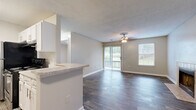 Located at 7545 Tara Rd in Jonesboro, Georgia, this single-floor residence offers a clean, modern aesthetic with a cohesive neutral color palette throughout. The living area is a standout feature, showcasing rich, dark wood-style flooring, a textured ceiling, and a ceiling fan with light fixture. A tile-surround fireplace anchors one wall, adding warmth and character to the space. Sliding glass doors flood the room with natural light and open to a private balcony with pleasant outdoor views, complemented by an additional window for cross-ventilation and brightness.

The kitchen is designed for functionality, featuring a galley-style layout with crisp white cabinetry, granite-style countertops, a stainless steel dishwasher, an electric range, and a refrigerator. The kitchen connects seamlessly to the living area via a half-wall pass-through, enhancing the open-concept feel. A dedicated laundry closet with hookups is conveniently accessible from the kitchen.

The bathroom is well-appointed with white cabinetry, granite-style countertops, a full tub-shower combination with safety grab bars, and wood-style flooring that ties the space together. The overall ambiance of the residence is bright, clean, and move-in ready, with consistent finishes that create a cohesive and welcoming environment throughout.