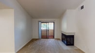 Located at 5845 Dew Ct in Rocklin, California, this single-story unit offers a thoughtfully designed layout with a comfortable mix of carpet and wood-style flooring. The living area serves as the centerpiece of the home, highlighted by a corner fireplace with a tile surround and a sliding glass door that opens to a private balcony overlooking mature trees, allowing natural light to fill the space.

The kitchen is open to the main living area and features white cabinetry, granite-style countertops, a peninsula for additional prep or seating, and stainless steel appliances including a gas range, over-the-range microwave, and refrigerator. Vaulted ceilings and a ceiling fan enhance the sense of openness in the adjoining dining and living space, which also benefits from wood-style flooring.

The bedroom is generously sized with plush carpet, a sliding closet with built-in shelving and hanging rods, and direct access to the bathroom. A separate bedroom area features natural light from corner windows with views of surrounding greenery. The bathroom is well-appointed with a white vanity, granite-style countertop, large mirror, and a full tub and shower combination with wood-style flooring completing the clean, functional design.