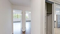 Located at 9502 Erickson Drive in Burnaby, BC, this 2-bedroom, 1-bathroom unit offers a thoughtfully designed layout with clean, modern finishes throughout. Light wood laminate flooring flows through the living areas and bedrooms, complementing the crisp white walls and creating a bright, cohesive atmosphere.

The open living room is a standout feature, with floor-to-ceiling windows that frame lush tree canopy views and allow generous natural light to fill the space. Baseboard heating runs beneath the windows, ensuring year-round comfort.

The kitchen is well-equipped with white cabinetry, subway tile backsplash, stainless steel appliances including a full-size refrigerator, and a peninsula with a dark quartz countertop — ideal for casual dining or meal prep. Tile flooring anchors the kitchen area.

The spacious primary bedroom comfortably accommodates large furnishings and features mirrored sliding closet doors with built-in storage. The second bedroom also benefits from natural light via a large window with greenery views. An additional dedicated closet with dual hanging rods provides extra storage.

The bathroom is finished with white subway tile surrounding the soaking tub, a stone-top vanity, and tile flooring, offering a clean and functional design. Overall, the unit presents a well-balanced living space in a natural setting.