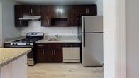 Located at 81 Hammell Place in Maywood, NJ, this single-floor unit offers a well-organized layout with consistent design choices throughout. Warm-toned hardwood flooring extends across the living areas and bedrooms, complemented by soft blue-gray walls and crisp white trim that create a calm, cohesive atmosphere.

The open living area is bright and welcoming, featuring recessed lighting, two windows that bring in natural light, and a staircase with white-painted balusters adding architectural character. A ceiling fan with integrated lighting is installed in one of the bedrooms, which also benefits from dual windows and a radiator for heating. Additional rooms share the same hardwood floors and neutral tones, offering flexibility in use.

The kitchen is outfitted with rich dark-wood cabinetry, granite-style countertops, a white subway tile backsplash, and stainless steel appliances including a gas range and refrigerator, alongside a dishwasher. Light wood-look flooring grounds the kitchen space.

The bathroom features a full tub-shower combo enclosed in white subway tile, a dark vanity with granite-style countertop, light tile flooring, and a small window for natural ventilation. The overall space is practical, well-maintained, and move-in ready.