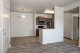 Located at 51 E Blue Heron Lane in Meridian, Idaho, this single-floor residence offers a well-organized layout designed for comfortable everyday living. The entry opens into a light-filled living area finished with wood-style laminate flooring that runs throughout the main living spaces. A peninsula kitchen connects seamlessly to the living room, featuring rich dark wood cabinetry, light countertops, a double basin sink, and black appliances including a refrigerator and range. The galley-style kitchen configuration maximizes storage and counter space, illuminated by overhead fluorescent lighting. The living area extends toward a sliding glass door that opens onto a private balcony, offering pleasant outdoor views of surrounding greenery. The bedroom is finished with plush carpet flooring and includes a window with natural light and neighborhood views. The full bathroom is clean and functional, appointed with dark wood vanity cabinetry, a single sink with a mirrored vanity, a full bathtub with shower, and wood-style flooring. Throughout the unit, neutral warm-toned walls and textured ceilings create a cohesive, understated aesthetic. The space is well-suited for those seeking a practical, move-in ready home in the Meridian area.