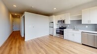 Located on the sixth floor at 2615 E 29th St in Minneapolis, this one-bedroom, one-bathroom apartment offers a clean, modern design across a thoughtfully arranged single-floor layout. Light-toned hardwood-style flooring runs throughout, complementing the crisp white walls and creating a bright, cohesive aesthetic.

The open living and kitchen area anchors the unit, featuring white cabinetry, stainless steel appliances including a range, microwave, and refrigerator, and a sink with a tile backsplash. The space flows efficiently, making the most of every square foot.

The bedroom is a comfortable, private retreat with a ceiling fan, a sliding double-door closet, and two large windows framed in dark trim that invite an abundance of natural light and offer elevated treetop views of the surrounding neighborhood. A wall-mounted HVAC unit ensures year-round climate control.

The bathroom is finished in a clean, minimalist style with a white vanity, a full soaking tub with shower, and consistent hardwood-style flooring. A dedicated laundry room adds exceptional convenience, housing a stacked full-size washer and dryer along with wire shelving for additional storage. A hallway connects the rooms, completing this efficient and well-appointed urban residence.