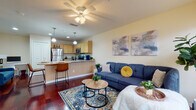 Located at 917 Apollo Beach Blvd in Apollo Beach, Florida, this single-floor residence offers a thoughtfully designed layout with a seamless flow between living, dining, and kitchen spaces. Rich hardwood flooring runs through the main living areas, anchoring a bright and welcoming atmosphere enhanced by a ceiling fan and natural light filtering through window treatments.

The open-concept kitchen is equipped with stainless steel appliances, including a refrigerator, range, and microwave, complemented by light maple cabinetry, granite countertops, and a breakfast bar with pendant lighting — ideal for casual dining or entertaining. The kitchen opens directly to the living room, which features a large sectional sofa, decorative area rug, and tasteful wall art, creating a comfortable and functional gathering space.

The bedroom offers plush carpeting, a generously sized window with curtain panels, and a serene, restful ambiance. A dedicated home office provides carpeted flooring, ample desk space, a window with blinds for natural light, and a quiet setting well-suited for productivity. The full bathroom includes tile flooring, a tub-shower combination with tile surround, and a vanity with granite countertops. Throughout, the unit maintains a consistent warm, neutral color palette with modern accents.