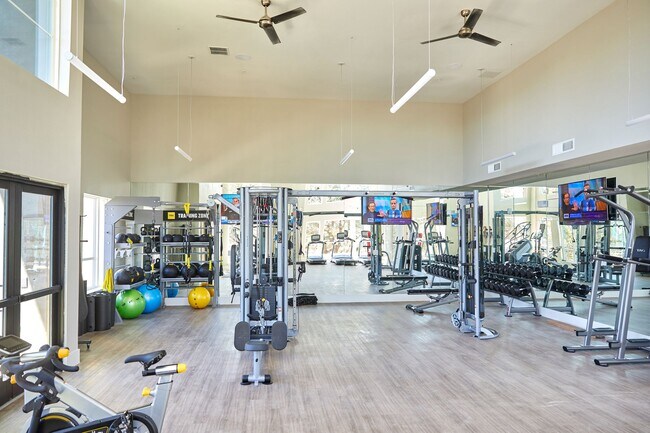 Sala de fitness bien equipada con pesas libres, equipos de acondicionamiento, cintas de correr y colchonetas de yoga. - Addison Medical Center Apartments