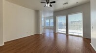 This 1,250 sq ft single-story residence offers a well-designed layout featuring 3 bedrooms, 2 bathrooms, and a seamlessly connected living, dining, and kitchen area. The open-concept living and dining space is anchored by rich hardwood-style flooring, a ceiling fan with light fixture, and large sliding glass doors that flood the room with natural light and provide outdoor views. The kitchen is equipped with stainless steel appliances including a gas range, microwave, and refrigerator, complemented by dark wood cabinetry, granite-style countertops, and tile flooring. High ceilings in the dining area feature elevated clerestory windows, adding to the airy feel of the space. The bedrooms are carpeted and receive natural light through large windows with views of palm trees and the surrounding neighborhood. The primary bedroom spans 180 sq ft and connects to a walk-in closet outfitted with multiple shelving units and hanging rods. The bathrooms feature tile flooring, dark wood vanities with granite countertops, and glass-enclosed walk-in showers with white tile surrounds. A dedicated in-unit laundry room houses a full-size washer and dryer with overhead shelving, completing this practical and comfortable home.