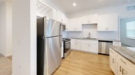 Located at 629 Wildlight Ave in Yulee, Florida, this single-story, three-bedroom, three-bathroom home offers a well-designed layout with a clean, modern aesthetic throughout. The heart of the home is an open-concept kitchen featuring crisp white shaker cabinetry, granite countertops, a subway tile backsplash, and a full suite of stainless steel appliances including a refrigerator, range, microwave, and dishwasher. A central island with pendant lighting above provides additional prep and seating space, flowing seamlessly into the adjoining living area. Light wood-style flooring runs through the kitchen and bathrooms, while plush carpeting adds comfort to all three bedrooms. Each bedroom is well-lit by windows with blinds and is equipped with a ceiling fan. The primary bedroom offers a generous footprint with vaulted ceiling detail, enhancing the sense of space. The three bathrooms are finished consistently with granite vanity tops, white cabinetry, and hardwood-style floors; at least one bathroom includes a full tub-shower combination. A connecting hallway ties the layout together efficiently. The home's neutral color palette and consistent finishes create a cohesive, move-in ready environment throughout.