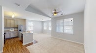 This single-story residence in Youngsville, Louisiana offers a thoughtfully designed open-concept floor plan that maximizes functionality and flow. The living area features soft carpeting, a vaulted tray ceiling accent, a ceiling fan, and multiple windows fitted with blinds that invite natural light while maintaining privacy.

The kitchen is a functional centerpiece, anchored by a curved granite-topped island with a sink and seating potential. Grey cabinetry extends to the ceiling for ample storage, complemented by granite countertops, wood-look flooring, and a full suite of stainless steel appliances including a refrigerator with ice maker, electric range, and microwave.

A hallway connects the private areas of the home, featuring a built-in corner granite desk—a practical niche ideal for a workspace. Both bedrooms are carpeted with ceiling fans and natural light from blinds-covered windows. The primary bedroom connects to a walk-in closet and an en-suite bathroom with a granite vanity. The second full bathroom mirrors this finish quality, featuring a granite vanity and a shower-tub combination. Wood-look flooring runs throughout the kitchen, hallways, and bathrooms, providing a cohesive aesthetic throughout the home.
