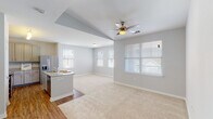 This single-story residence in Youngsville, Louisiana offers a thoughtfully designed open-concept floor plan that maximizes functionality and flow. The living area features soft carpeting, a vaulted tray ceiling accent, a ceiling fan, and multiple windows fitted with blinds that invite natural light while maintaining privacy.

The kitchen is a functional centerpiece, anchored by a curved granite-topped island with a sink and seating potential. Grey cabinetry extends to the ceiling for ample storage, complemented by granite countertops, wood-look flooring, and a full suite of stainless steel appliances including a refrigerator with ice maker, electric range, and microwave.

A hallway connects the private areas of the home, featuring a built-in corner granite desk—a practical niche ideal for a workspace. Both bedrooms are carpeted with ceiling fans and natural light from blinds-covered windows. The primary bedroom connects to a walk-in closet and an en-suite bathroom with a granite vanity. The second full bathroom mirrors this finish quality, featuring a granite vanity and a shower-tub combination. Wood-look flooring runs throughout the kitchen, hallways, and bathrooms, providing a cohesive aesthetic throughout the home.