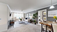 This single-floor, 2-bedroom, 2-bathroom residence is thoughtfully designed to maximize comfort and functionality. The open-concept living and dining area serves as the heart of the home, featuring plush carpet, crown molding, and a ceiling fan overhead. A bold gray accent wall anchors the living room, which benefits from generous natural light streaming through large windows dressed with white curtains. The adjacent dining area continues the gray accent wall theme, illuminated by a pendant track light fixture.

The kitchen is equipped with dark espresso cabinetry, granite-style countertops, a tile backsplash, and black appliances including a range, microwave, and refrigerator, all set on tile flooring. A pantry provides additional storage convenience.

The primary bedroom offers a comfortable, carpeted retreat with a ceiling fan, natural light from a window with views to the outdoors, and access to a walk-in closet featuring wire shelving. The second bedroom is equally well-sized. Both bathrooms include a vanity with ample counter space, a tub-shower combination, and wood-look flooring. A dedicated laundry area and a hallway complete the layout, making this a highly functional and well-organized residence.